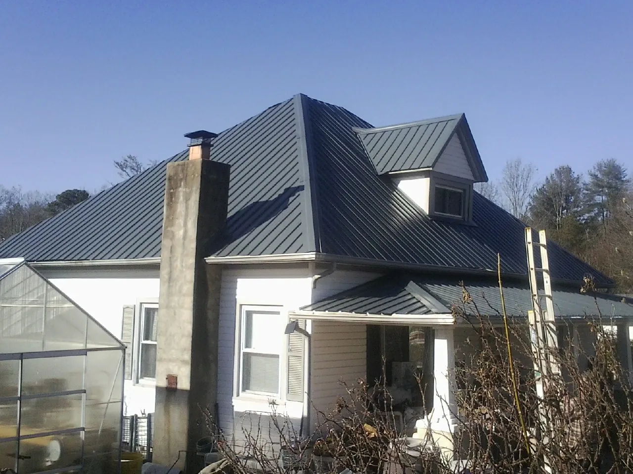 Dark blue standing seam metal roof on a white farmhouse with dormer — Slate & Tile Roof Repair by Roofing Brothers in Union Mills