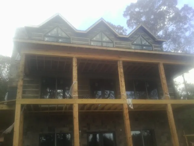 Dormers and porch framing on a large log home under construction — Roof Coating work by our crew in Union Mills