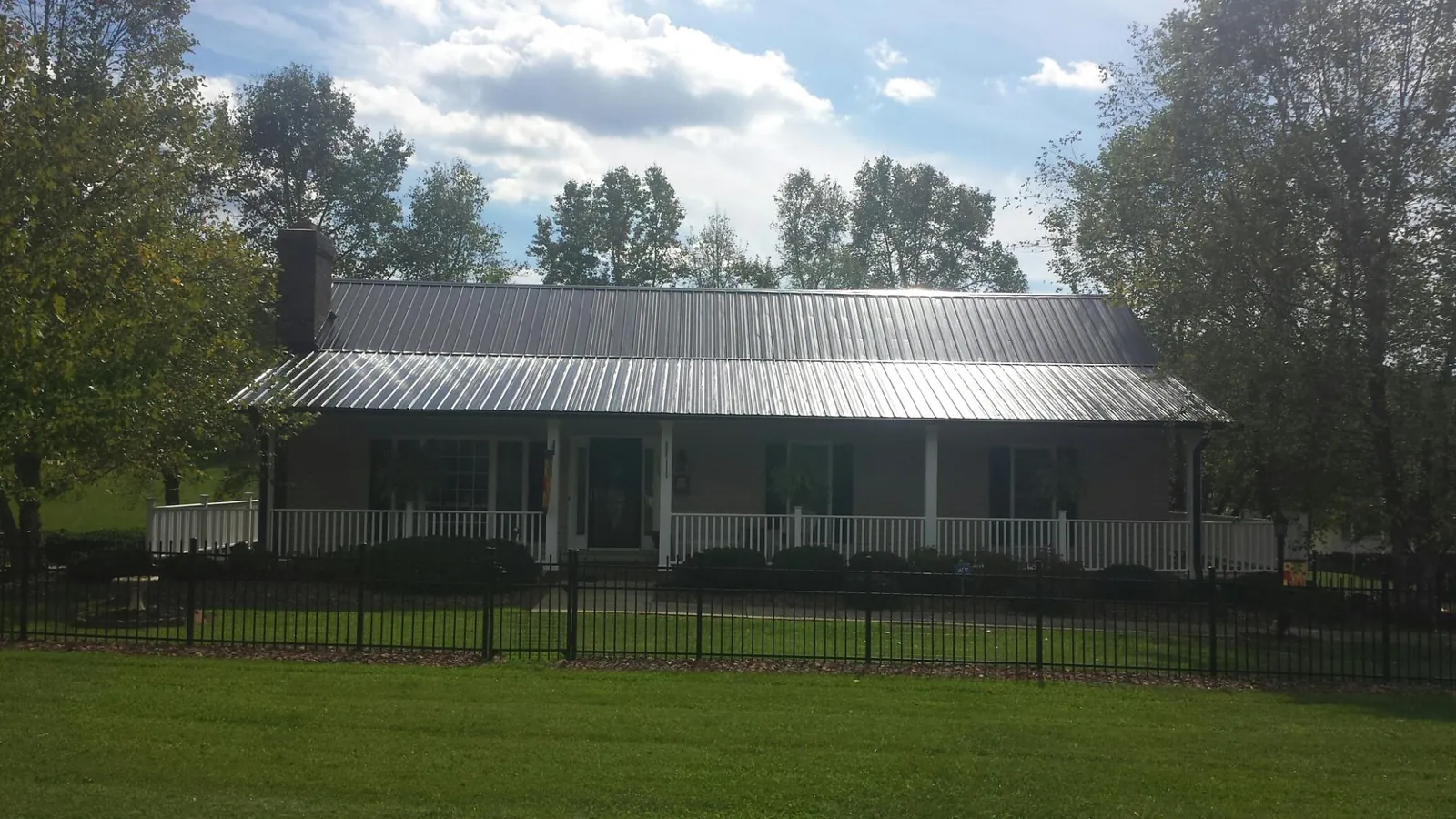 Gray metal roof on a brick ranch with a full width front porch — Gutter Guard Installation work by our crew in Union Mills